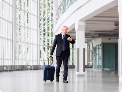 Businessman walking through modern office corridor with luggage, representing an active professional lifestyle