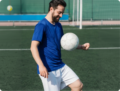 Active man playing football on outdoor pitch, representing improved mobility from joint care treatment
