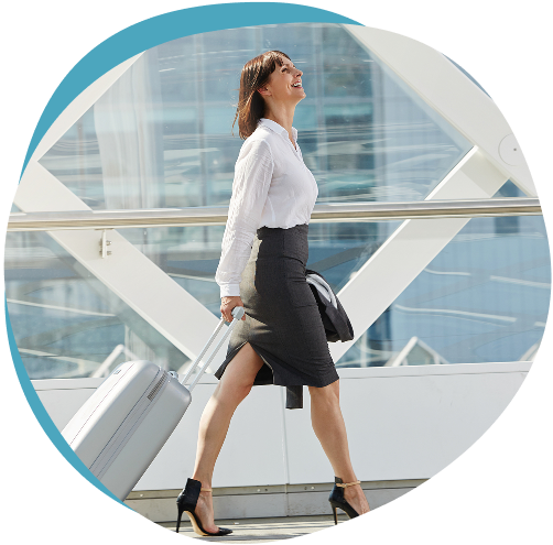 Businesswoman walking confidently through airport with luggage, representing active mobility from joint care treatment