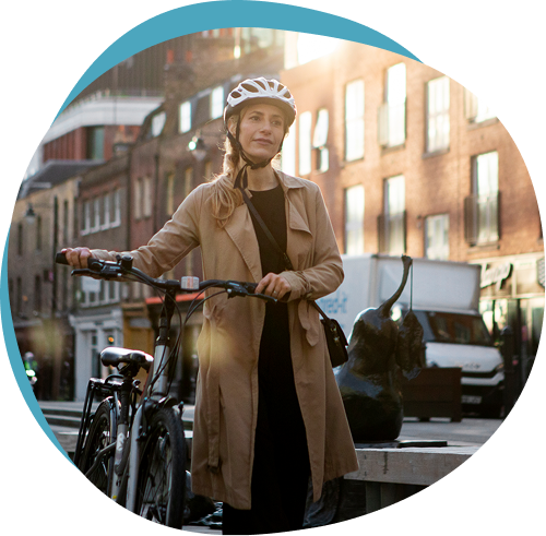 Woman wearing a helmet standing with her bicycle on a city street